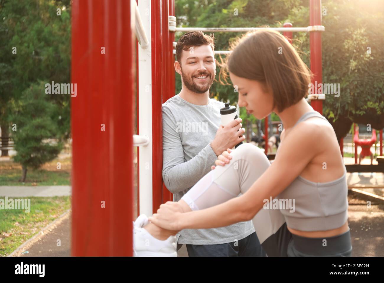 Young man with bottle of water and his wife on sport ground Stock Photo ...