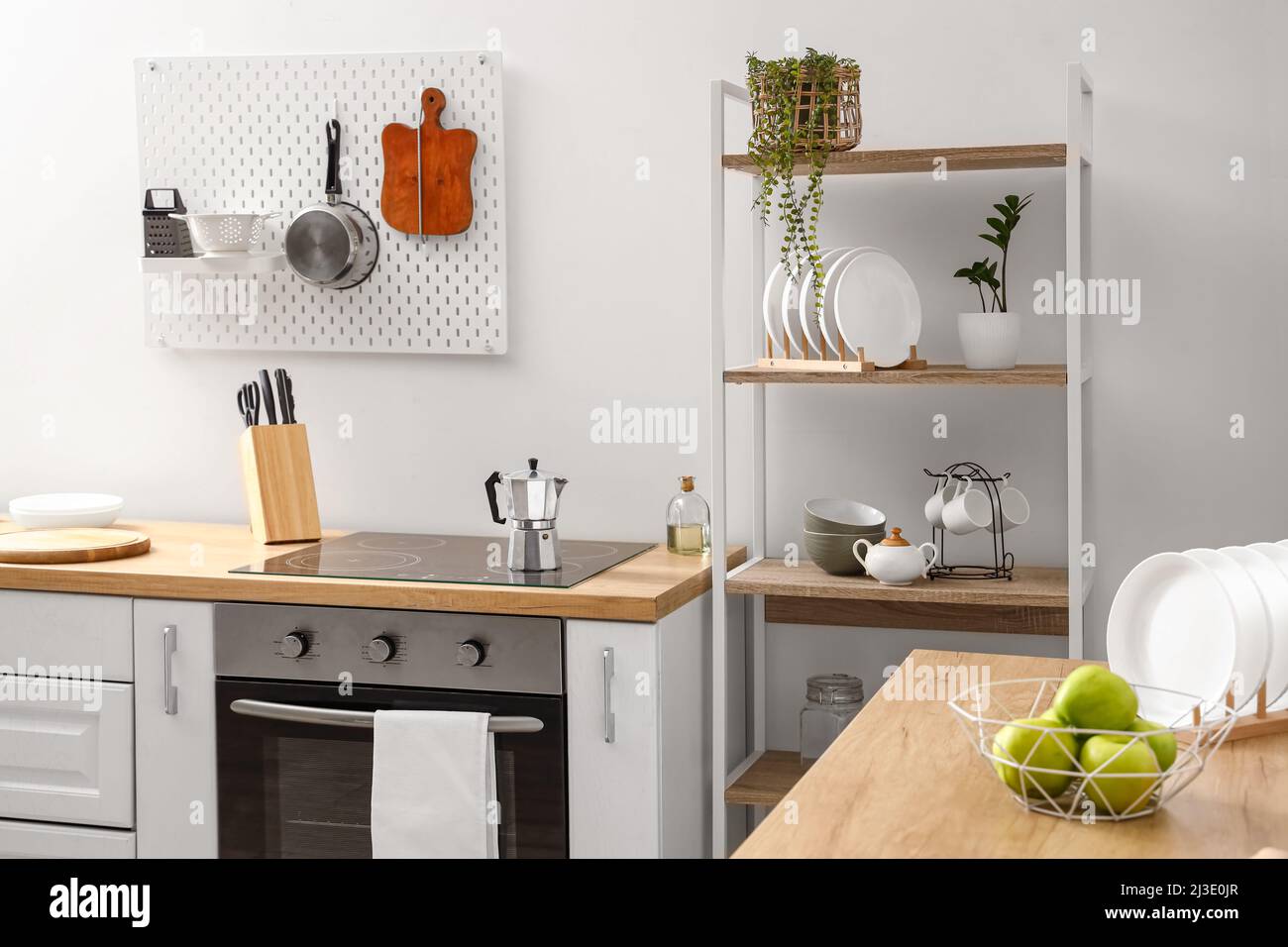 Modern shelving unit, pegboard and kitchen counter with stove near ...