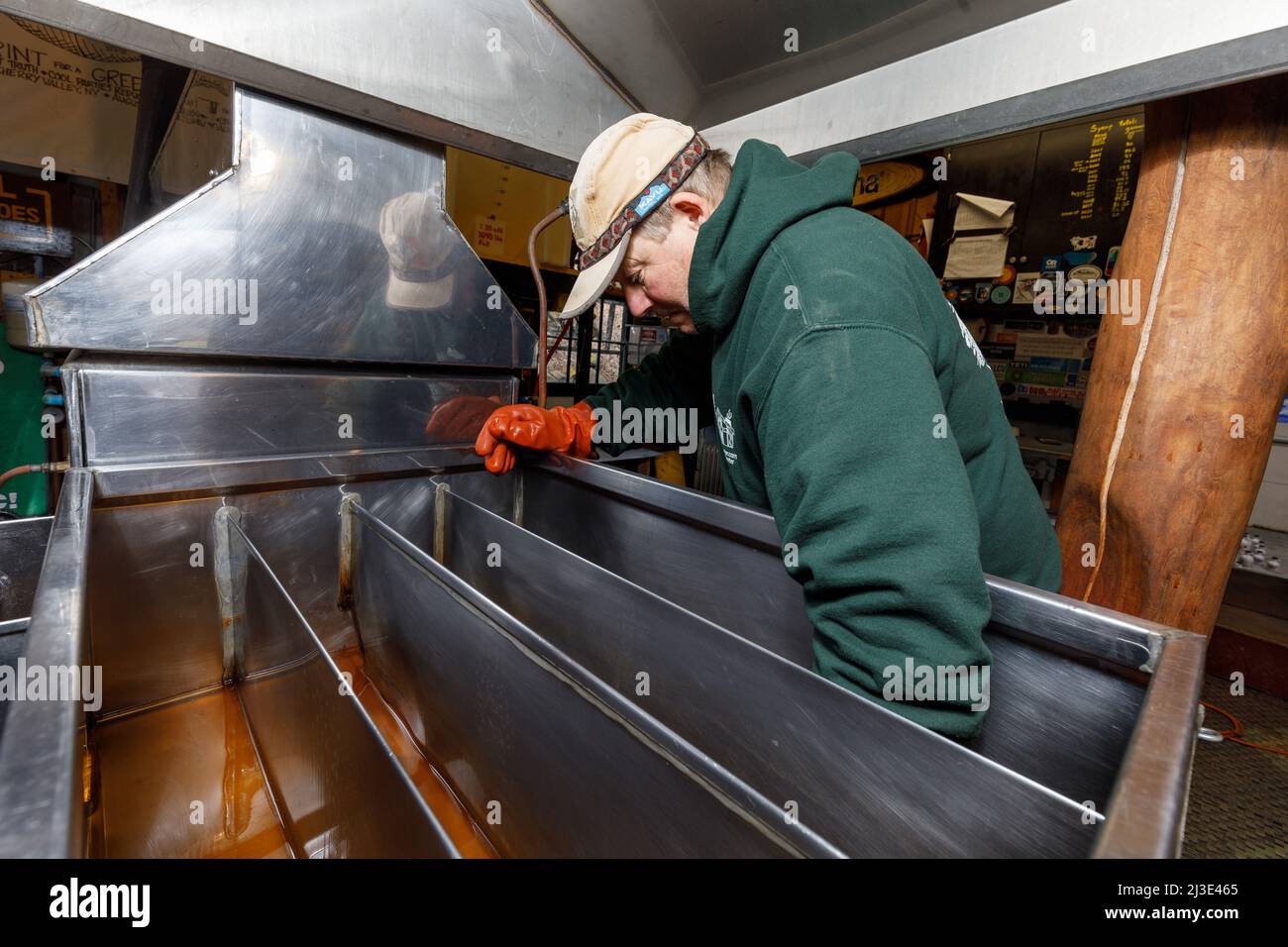 Making maple syrup: Man cleans 'sugar sand' out of his evaporator. Cherry Valley, Otsego County, New York State. Stock Photo