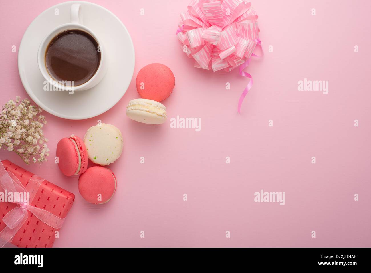 Flat-lay coffee with macaroons with a gift and flowers with an empty
