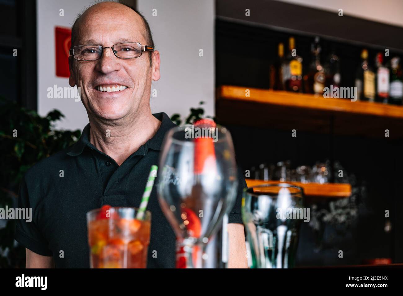 portrait of a mature waiter carrying a tray of beverages Stock Photo