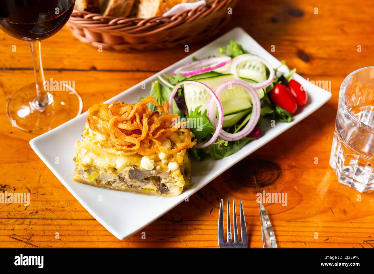 Quiche Lorraine slice with fried onions and vegetable salad Stock Photo