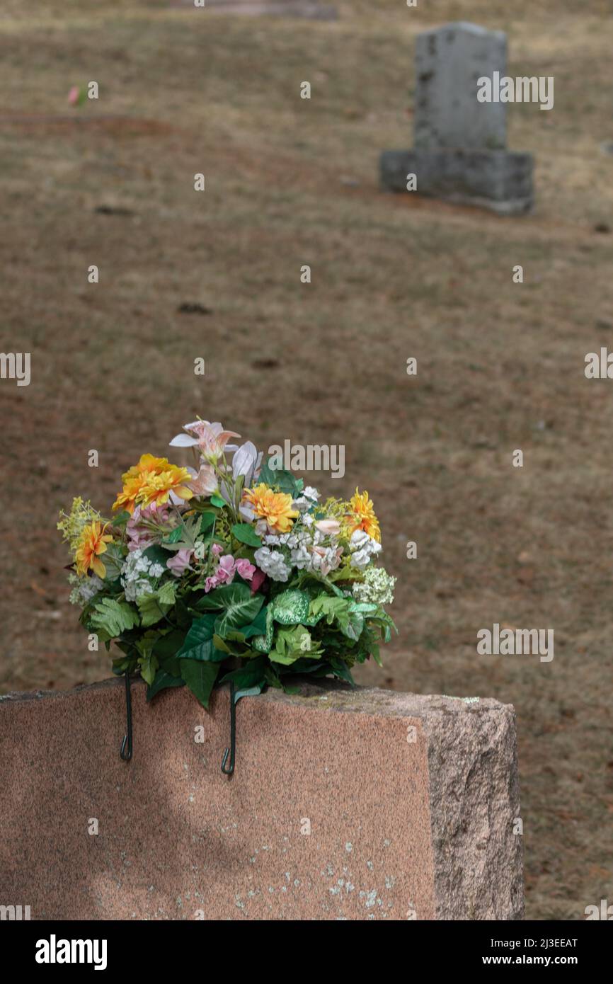 A colourful flower bouquet on a tombstone in a graveyard in springtime