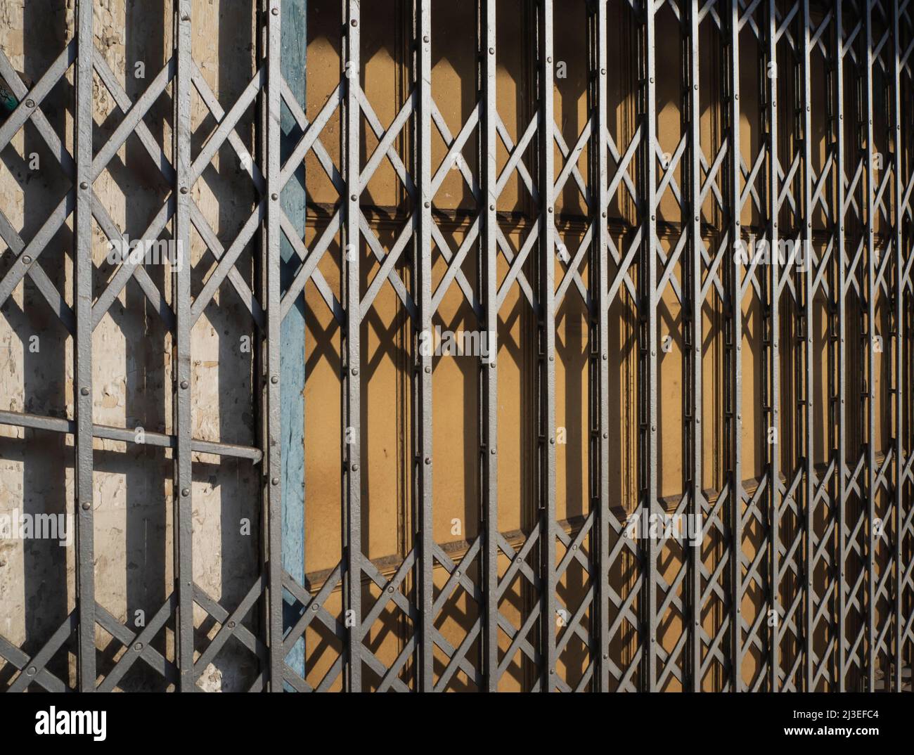 An old, rusty metal grill gate in front of wooden doors Stock Photo