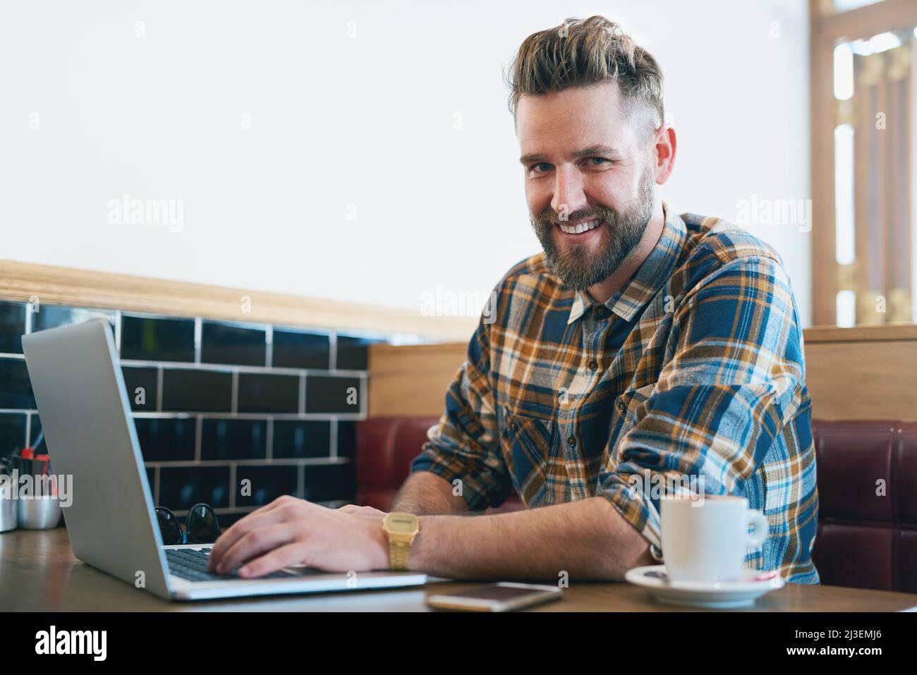 No coffee, no workee. Portrait of a young man using his laptop while sitting in a cafe. Stock Photo