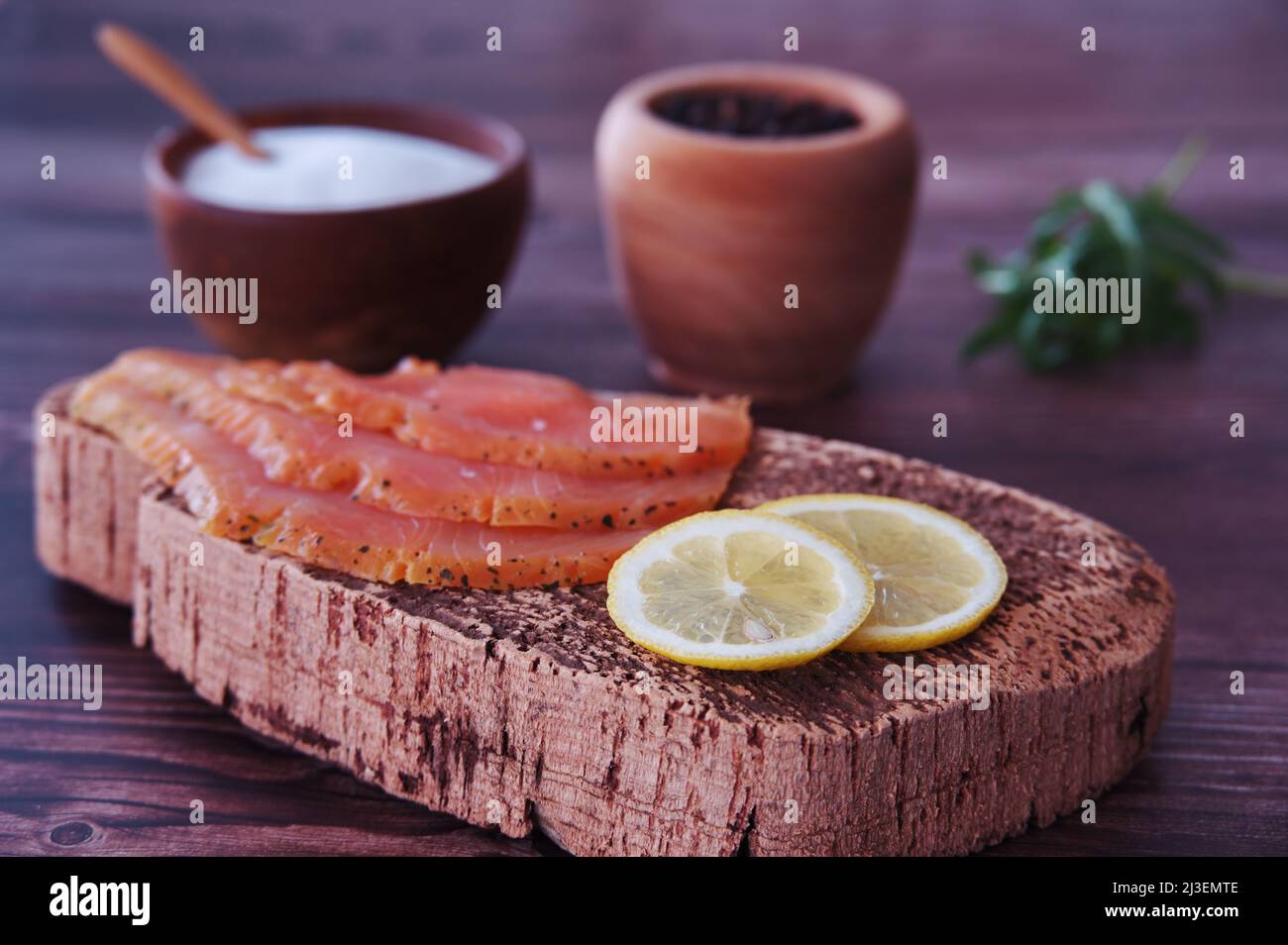 Smoked salmon fillets with lemon, salt and pepper on cutting board ...