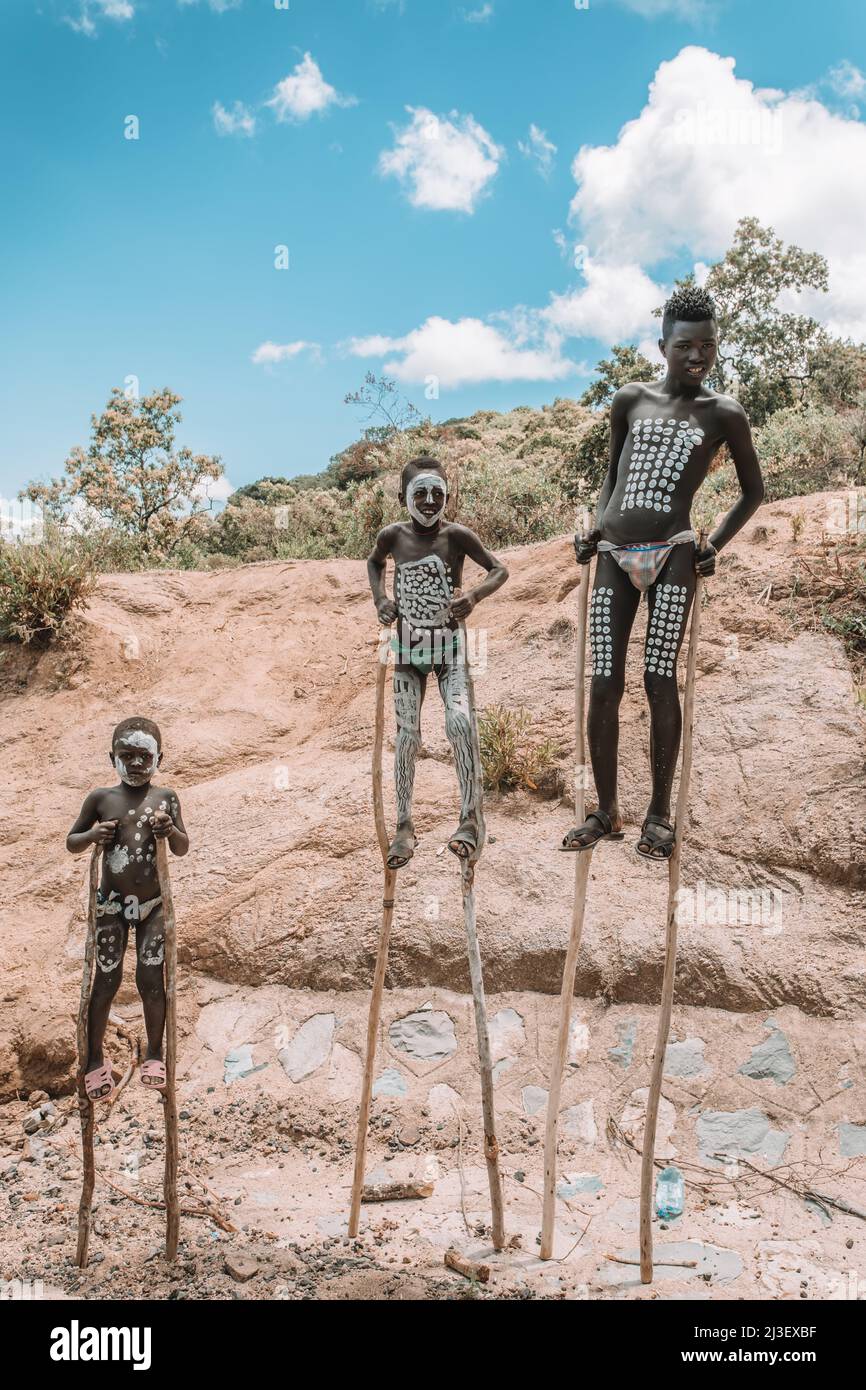 Southern Nations region, Ethiopia - May 10, 2019: Unknown happy Banna boy with traditional body painting walking on stilts in Southern Nations region, Stock Photo