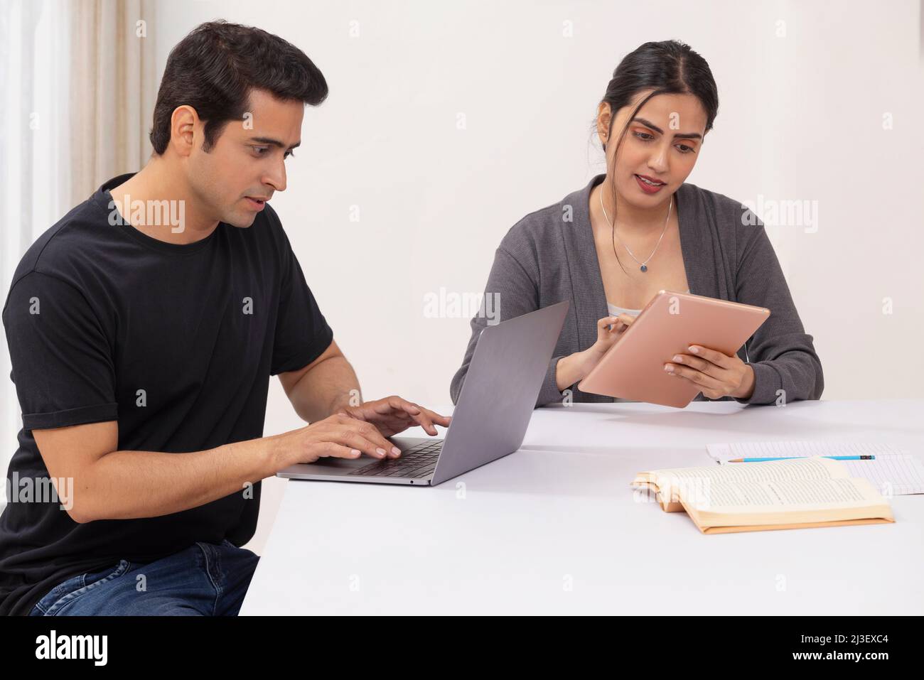 Couple working from home using laptop and digital tablet Stock Photo