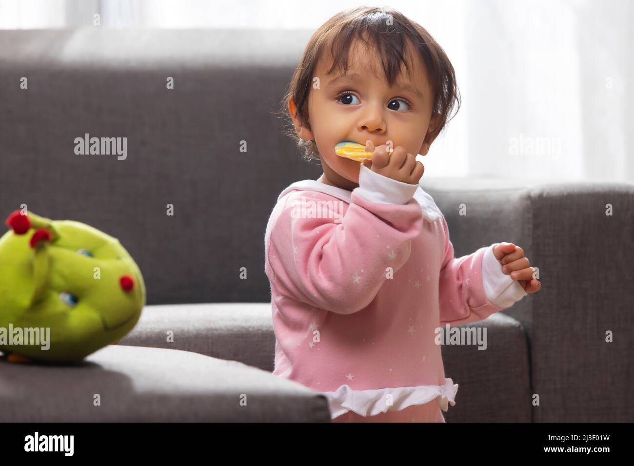 Cute baby chewing toy and looking away Stock Photo Alamy