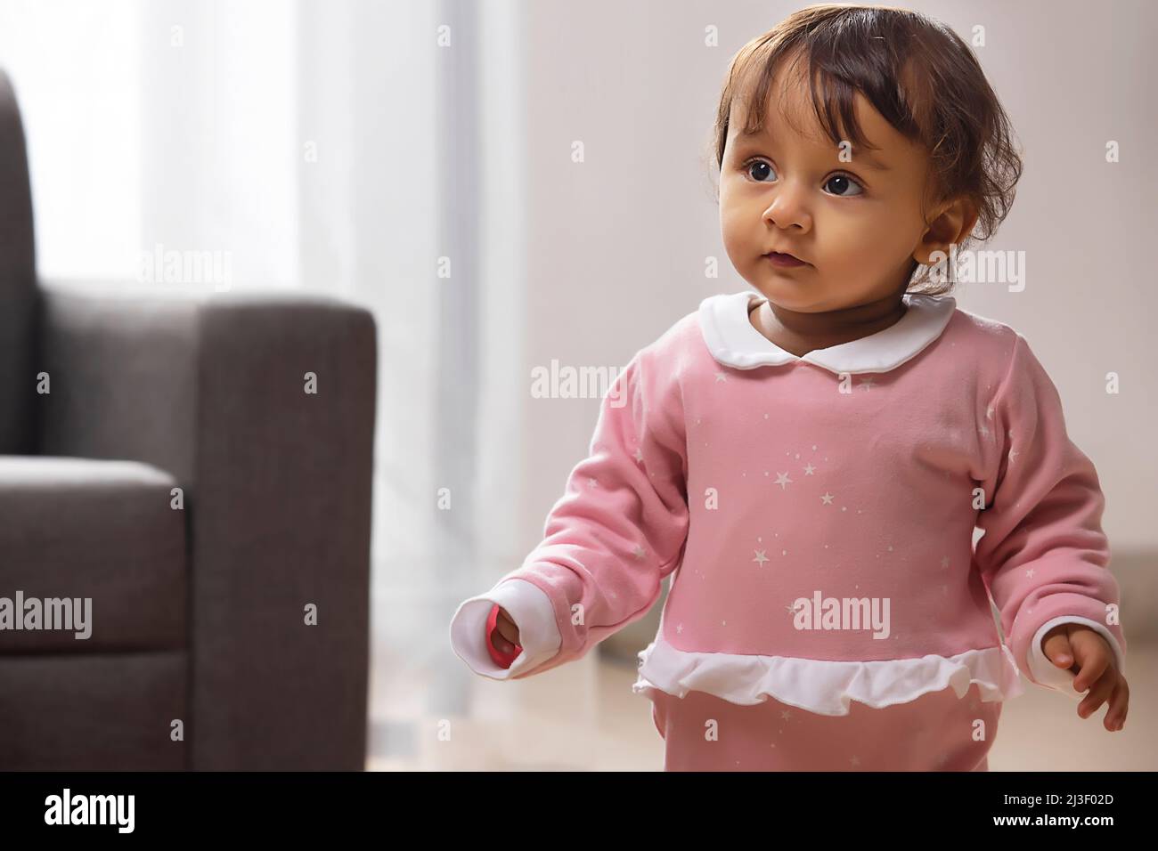 Cute baby looking away while standing in living room at home Stock Photo