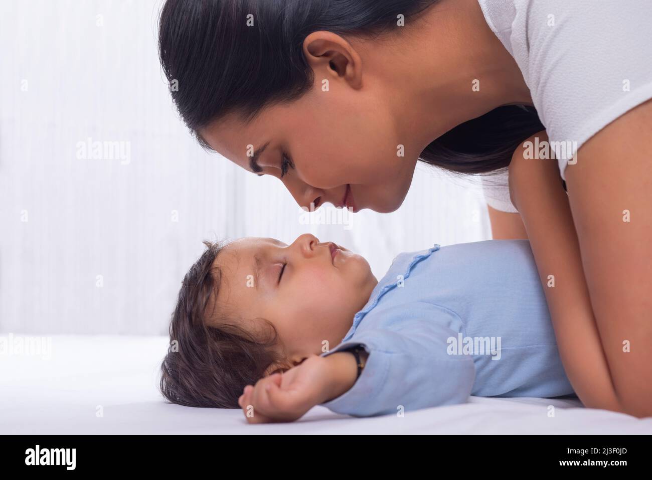 Portrait of mother kissing sleeping baby's cheek Stock Photo