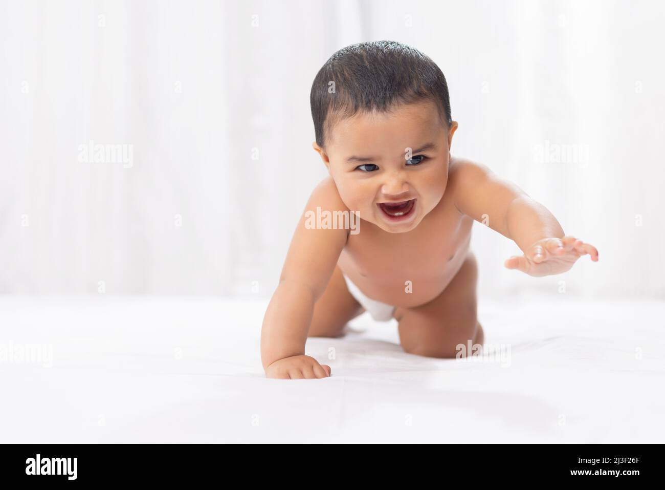 Cute baby in diaper crawling on bed Stock Photo