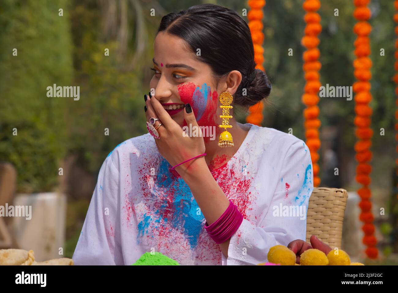 Portrait happy woman looking elsewhere with hand on mouth on Holi Stock Photo