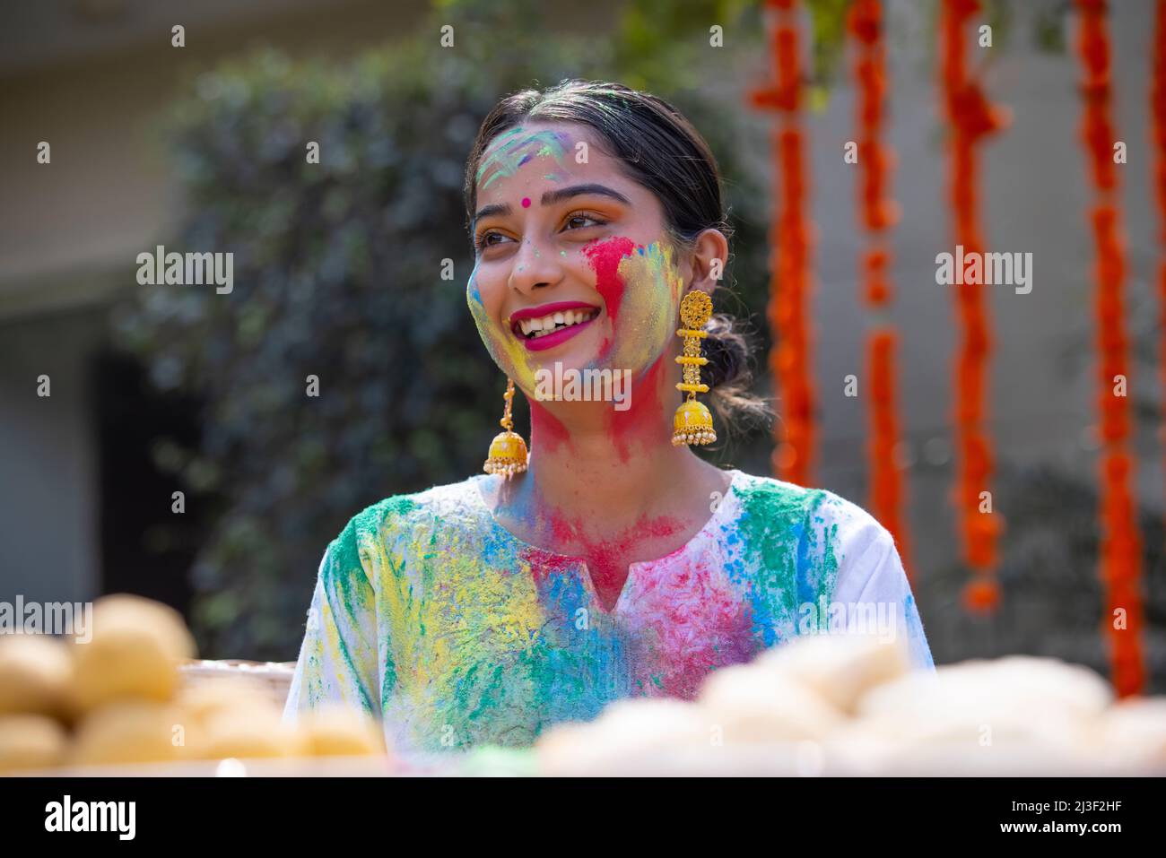 Portrait happy young woman looking elsewhere with colourful face on Holi Stock Photo