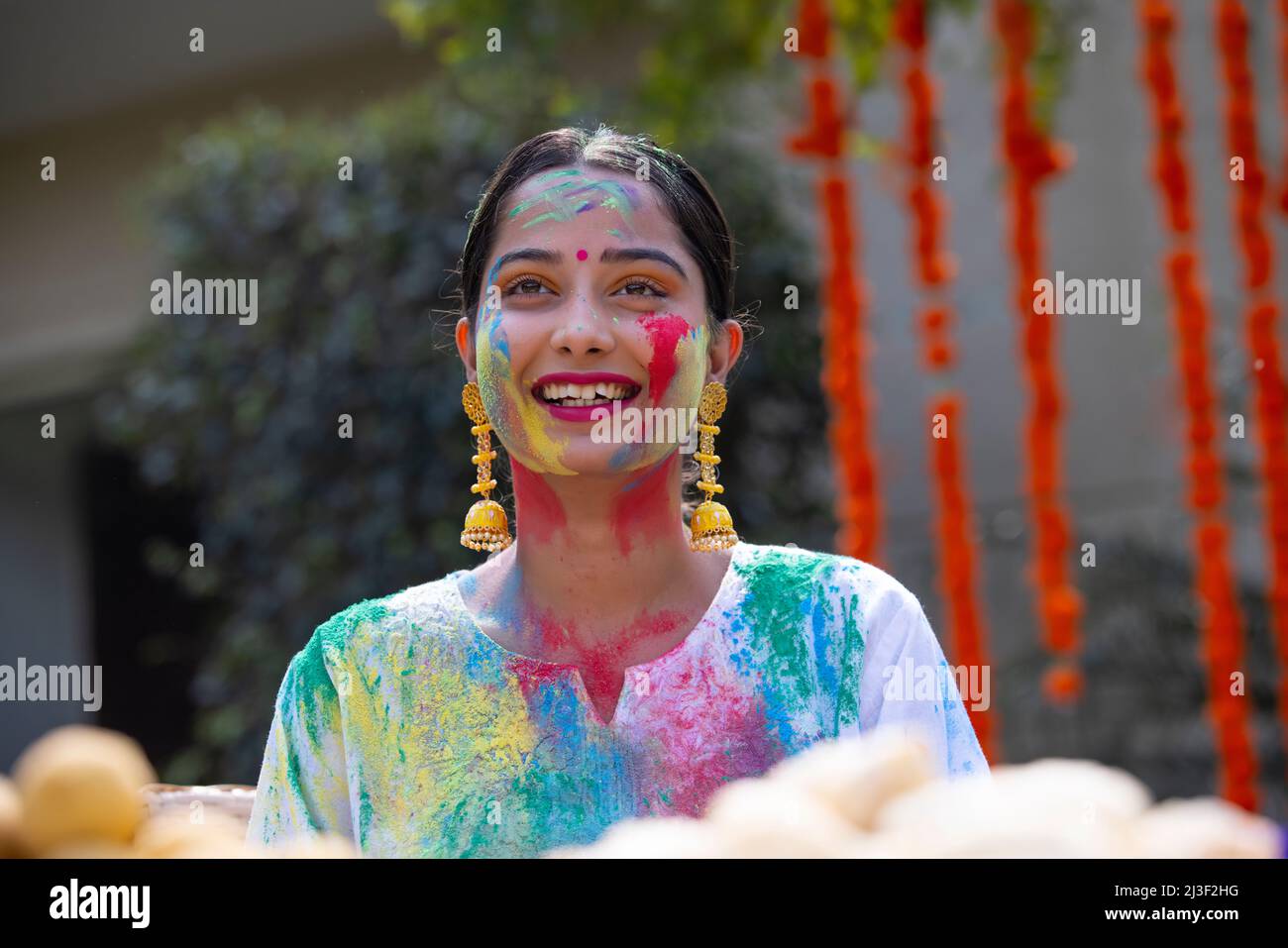 Portrait happy young woman looking elsewhere with colourful face on Holi Stock Photo