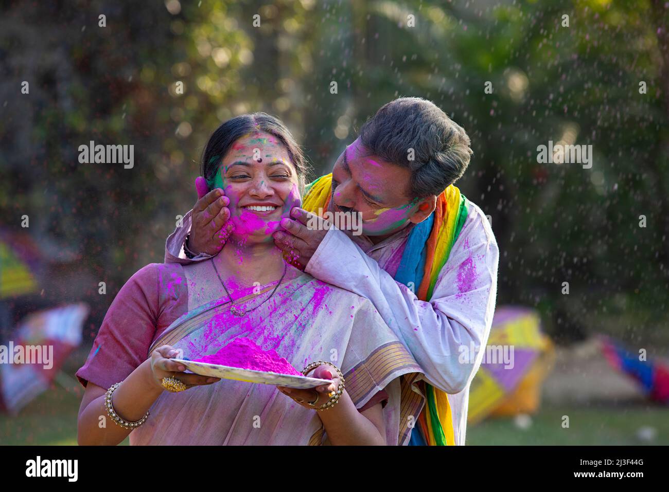 Happy middle aged couple celebrating Holi with dry colours Stock Photo