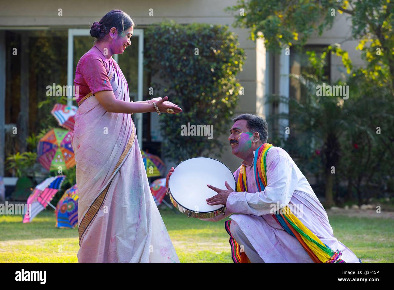 Happy middle aged couple enjoying Holi festival by playing drum Stock Photo