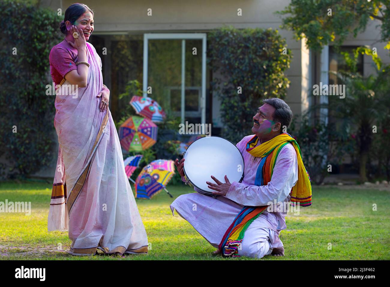 Happy middle aged couple enjoying Holi festival by playing drum and dancing Stock Photo