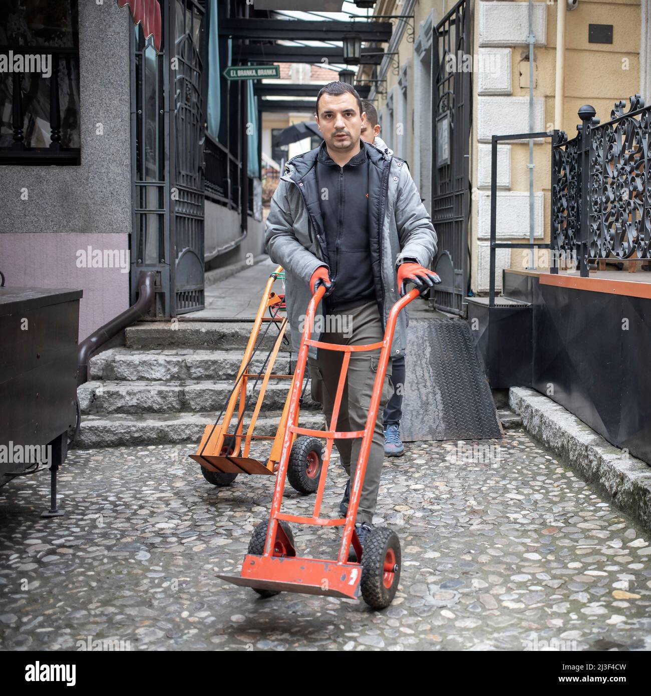 Belgrade, Serbia, Apr 7, 2022: Worker pushing empty upright trolley after delivery Stock Photo