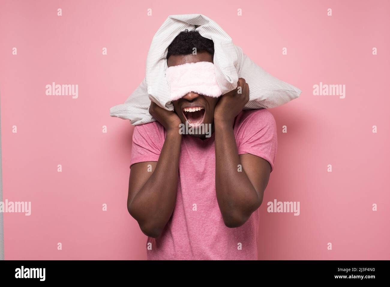 African man shouting with an angry expression and holding a pillow Stock Photo