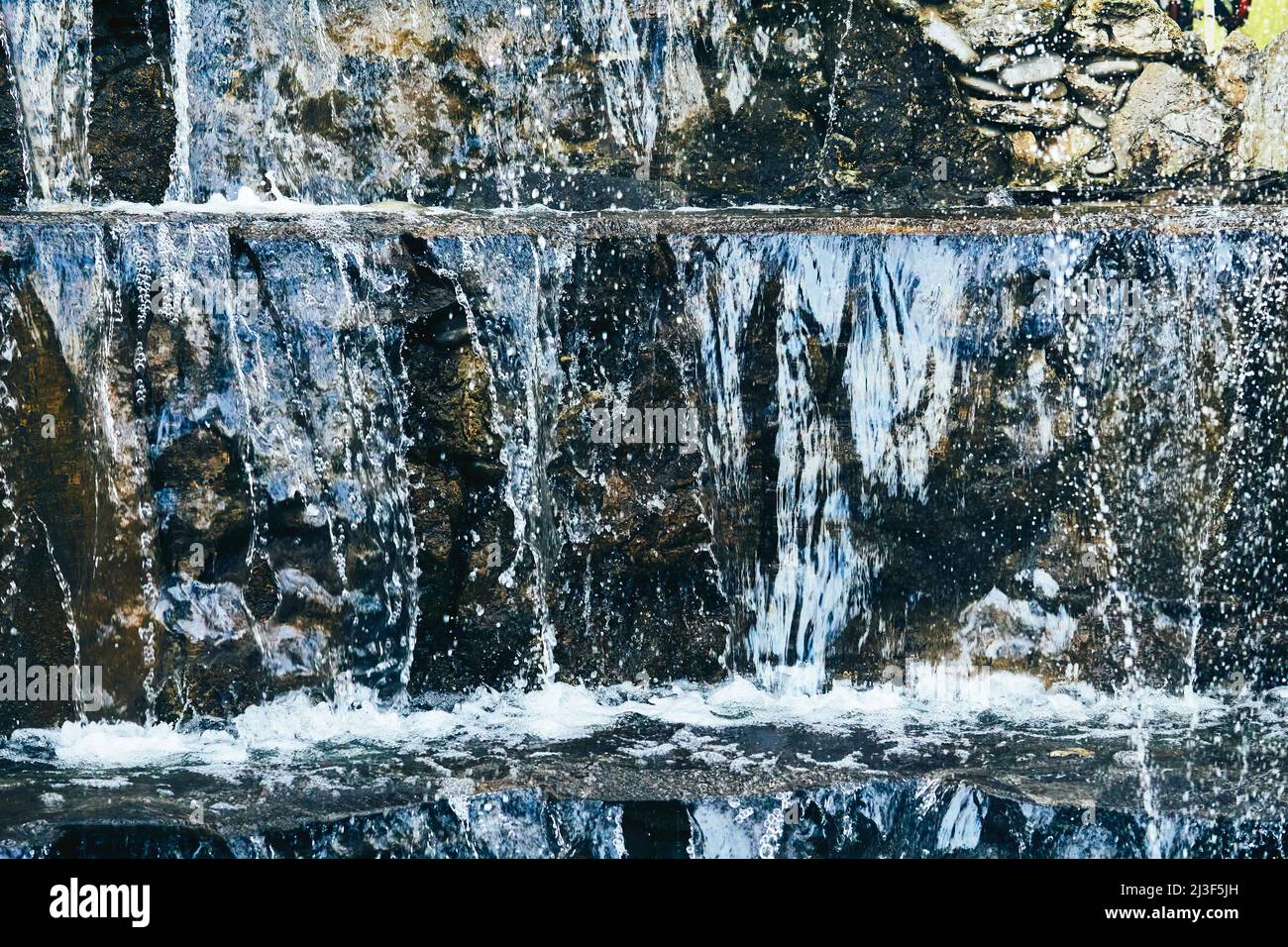 Pure mineral blue water flows over stepped mountain stones Stock Photo
