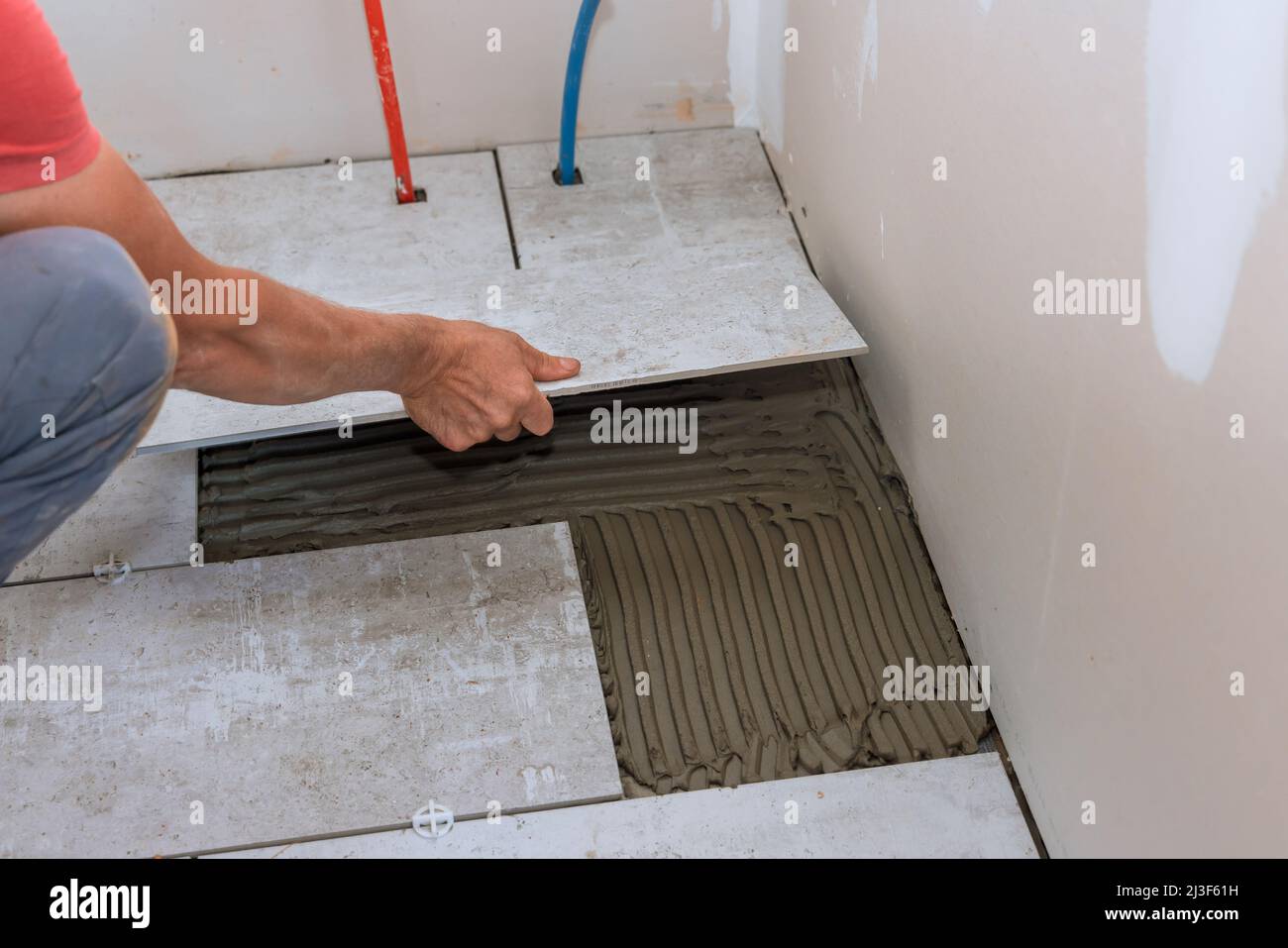 Placing ceramic floor tiles on adhesive surface leveling Stock Photo