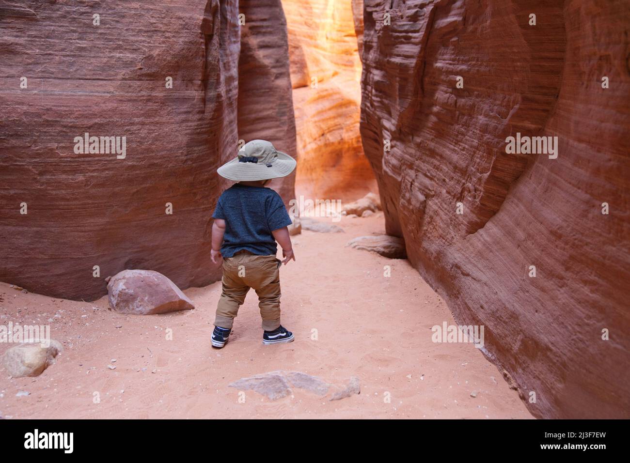 Caucasian toddler boy with a safari hat standing inside Wirepass Canyon near Buckskin Gulch, Coyote Buttes. Stock Photo