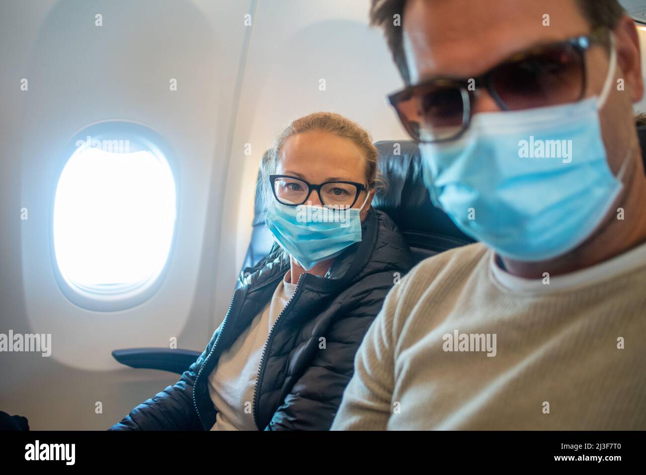 A young couple wearing face masks while traveling on airplane. New