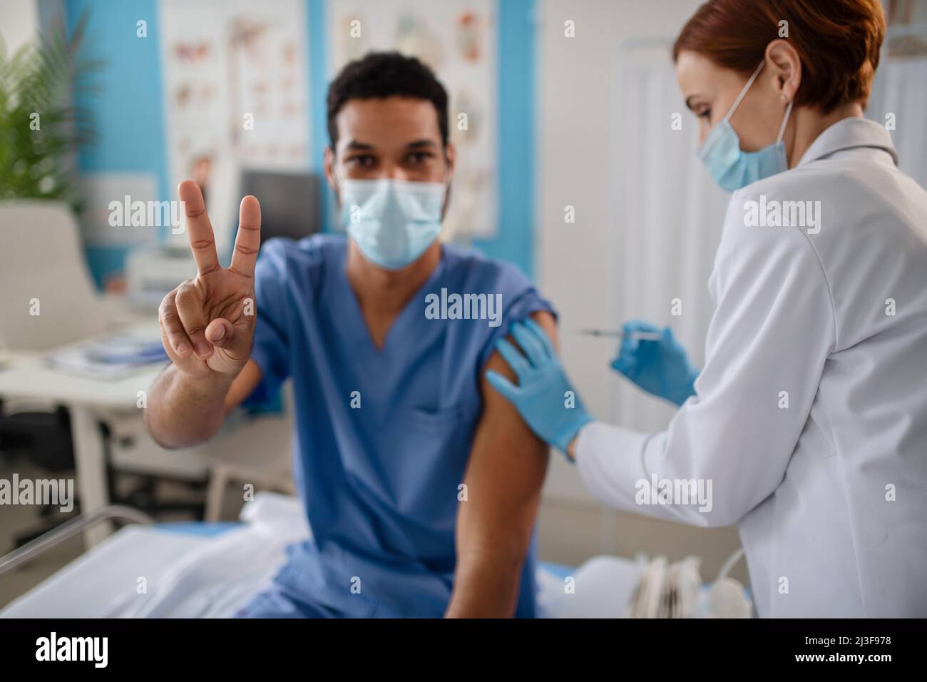 Doctor getting covid-19 vaccince from his colleague. Stock Photo