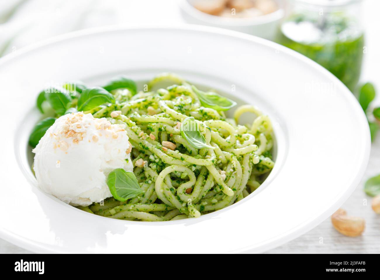 Pasta with basil pesto, cashew nuts and soft cream cheese Stock Photo