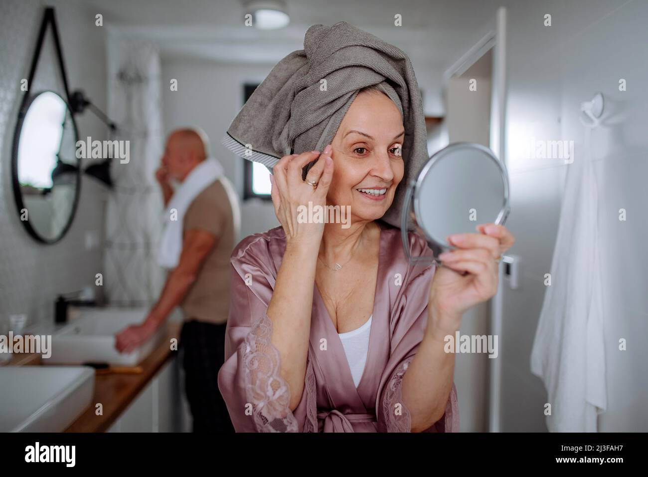 Senior couple in bathroom, brushing teeth and looking at mirror, morning routine concept. Stock Photo