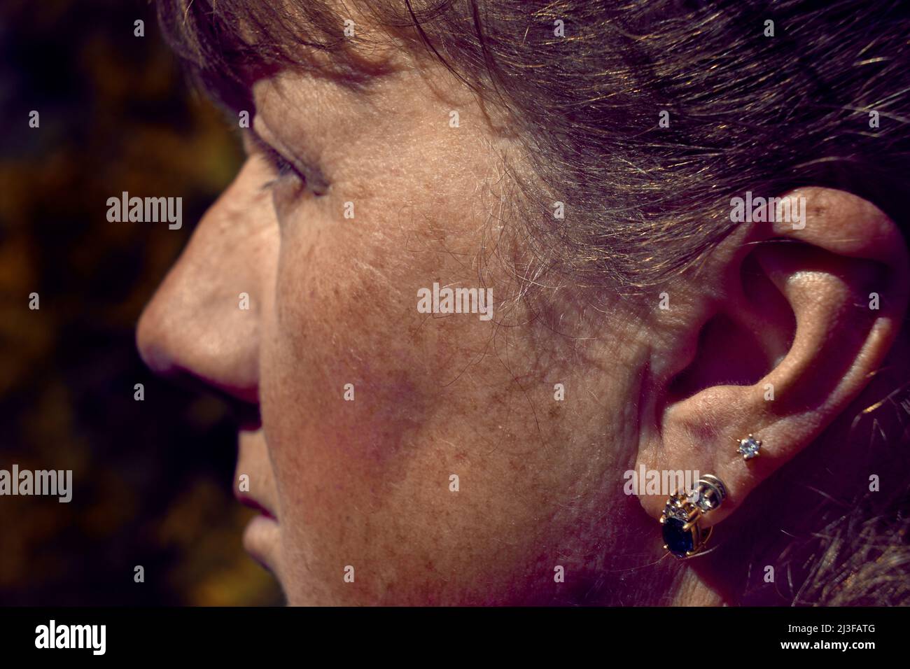 Portrait of a pensive pretty adult mature woman with earrings in her ear Stock Photo
