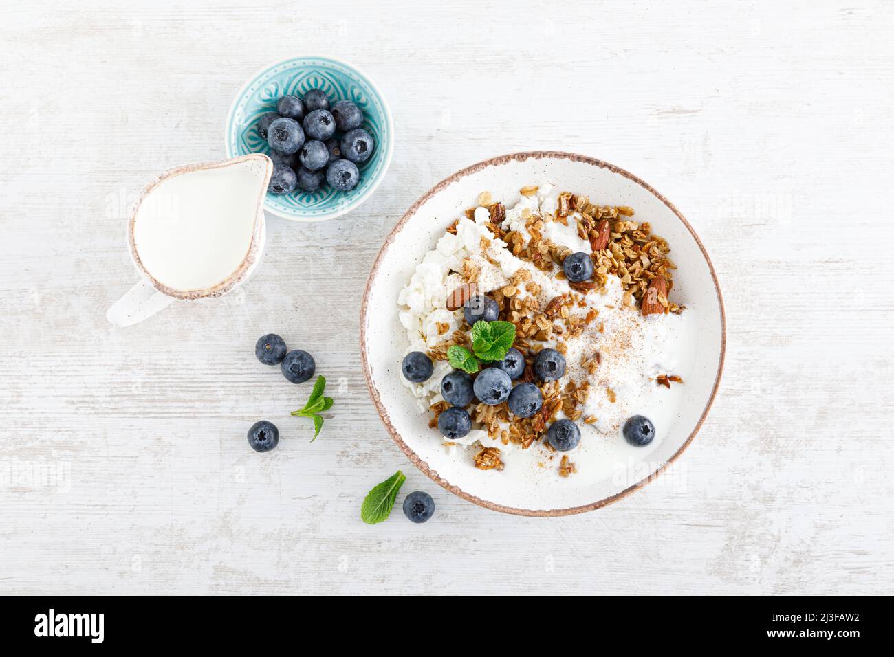Bowl of granola with fresh blueberry, cottage cheese or curd, yogurt and nuts. Healthy food. Breakfast. Top view Stock Photo
