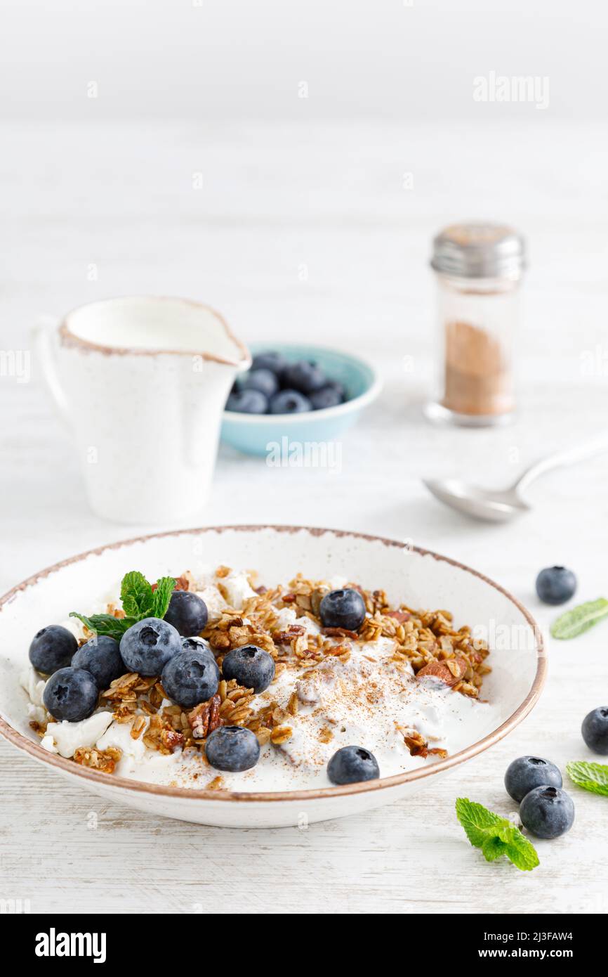 Bowl of granola with fresh blueberry, cottage cheese or curd, yogurt and nuts. Healthy food. Breakfast Stock Photo