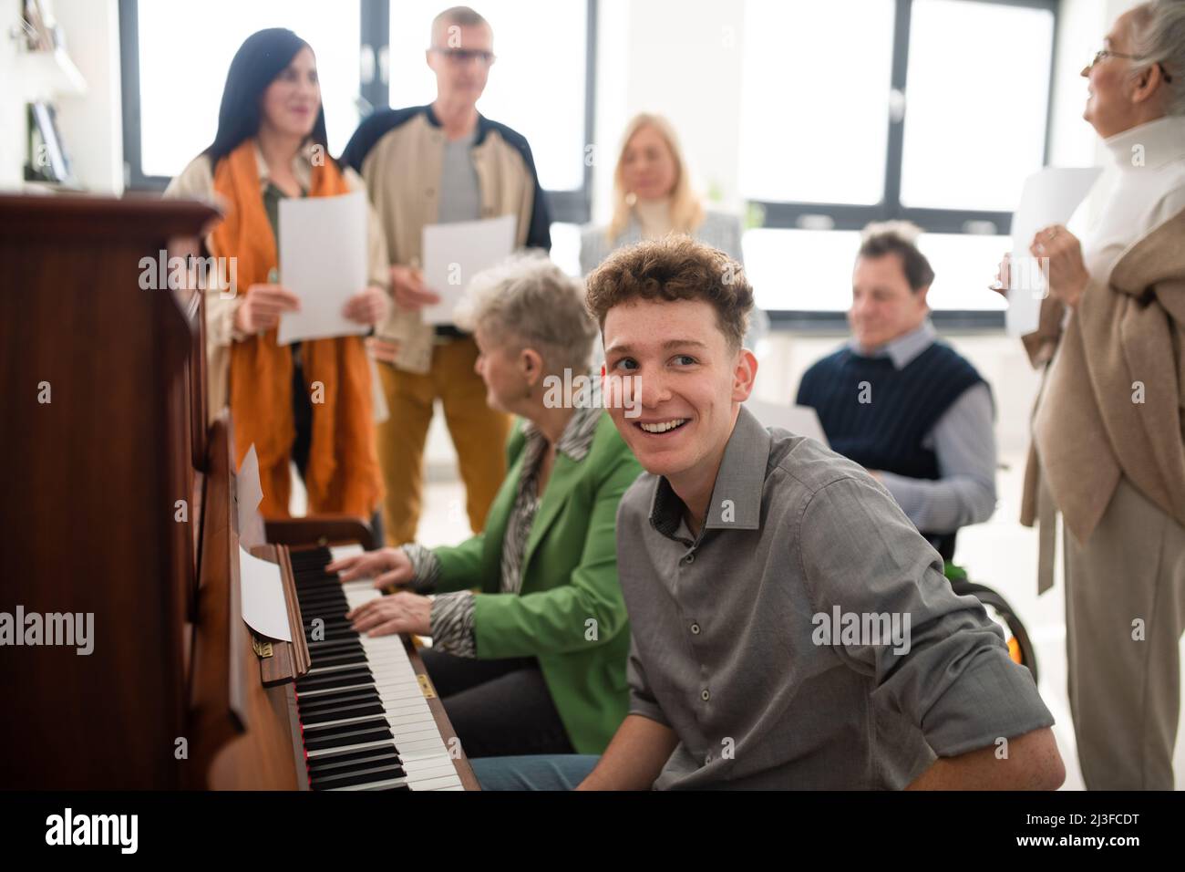 Group of seniors with young teacher singing together at choir rehearsal. Stock Photo