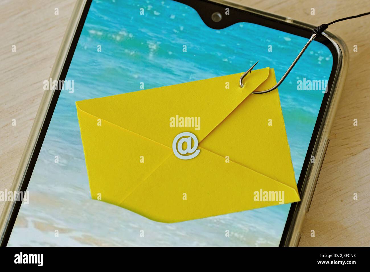 Email envelope caught with fishing hook on mobile phone - Phishing and mobile phone security concept Stock Photo