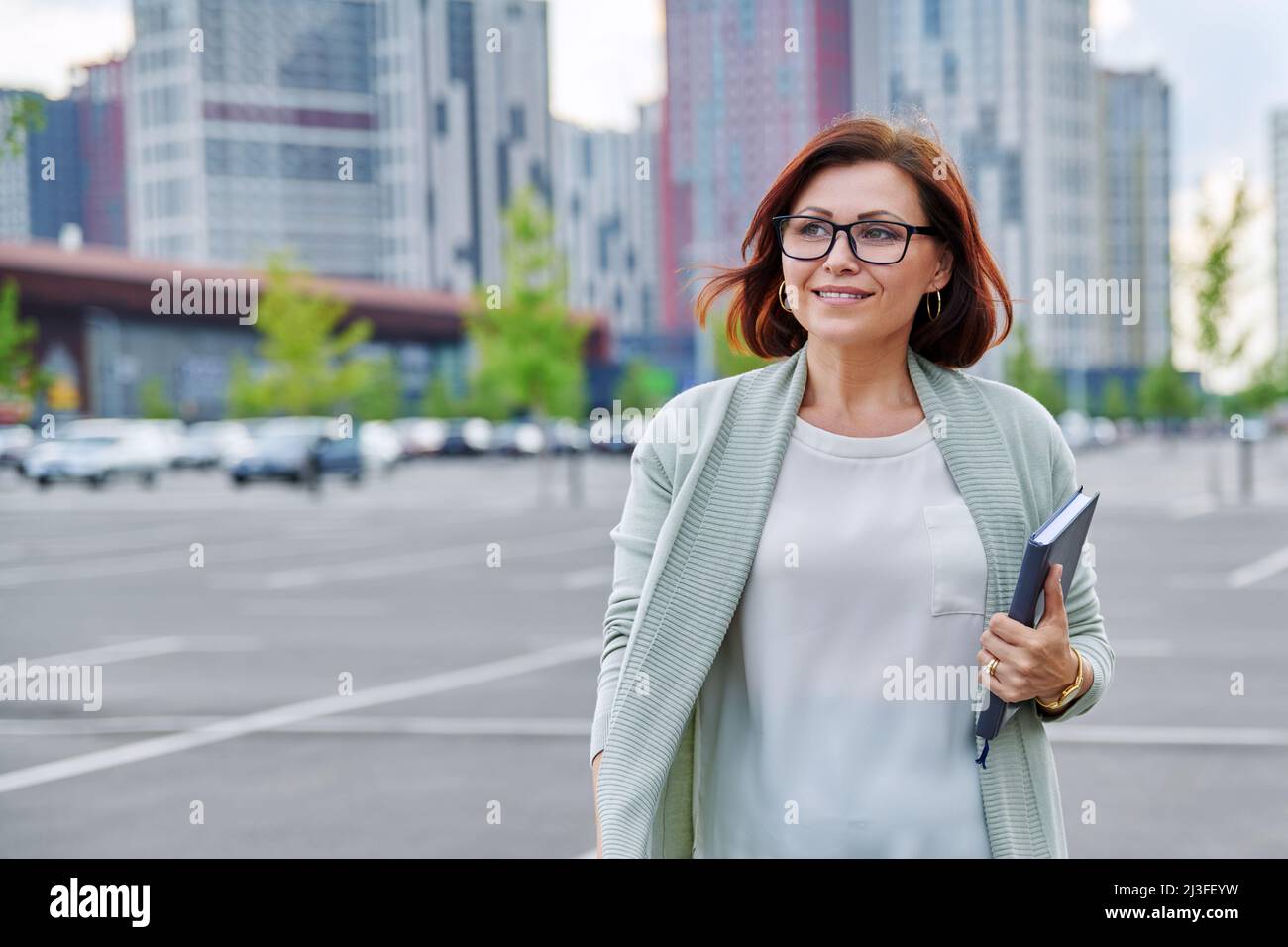 Smiling successful mature business woman walking outdoor, modern urban style background. Stock Photo