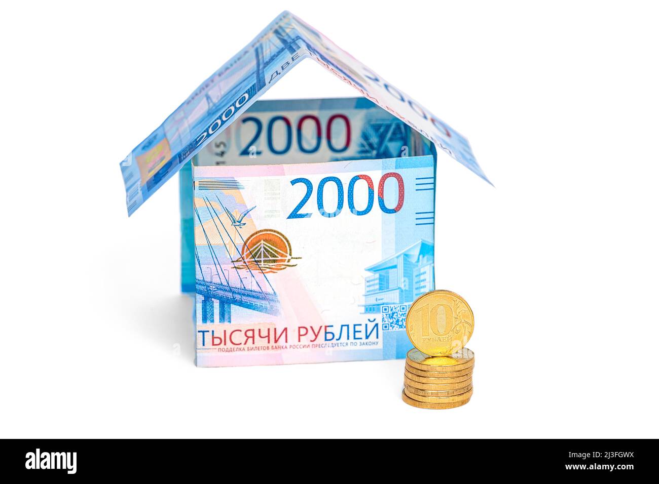 A house made of ruble notes and a stack of coins isolated on a white ...