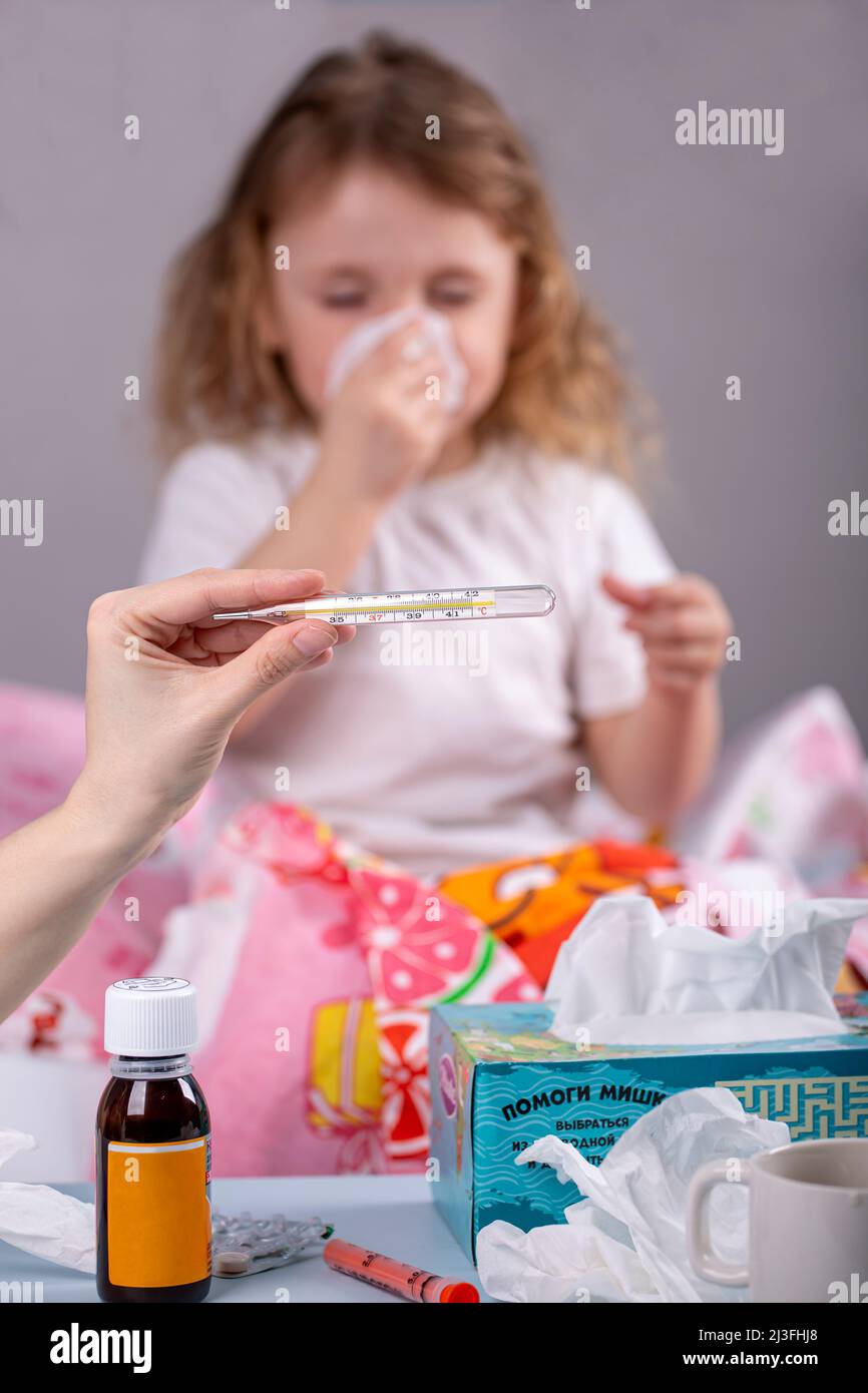 Mom shows a mercury thermometer with a high temperature against the