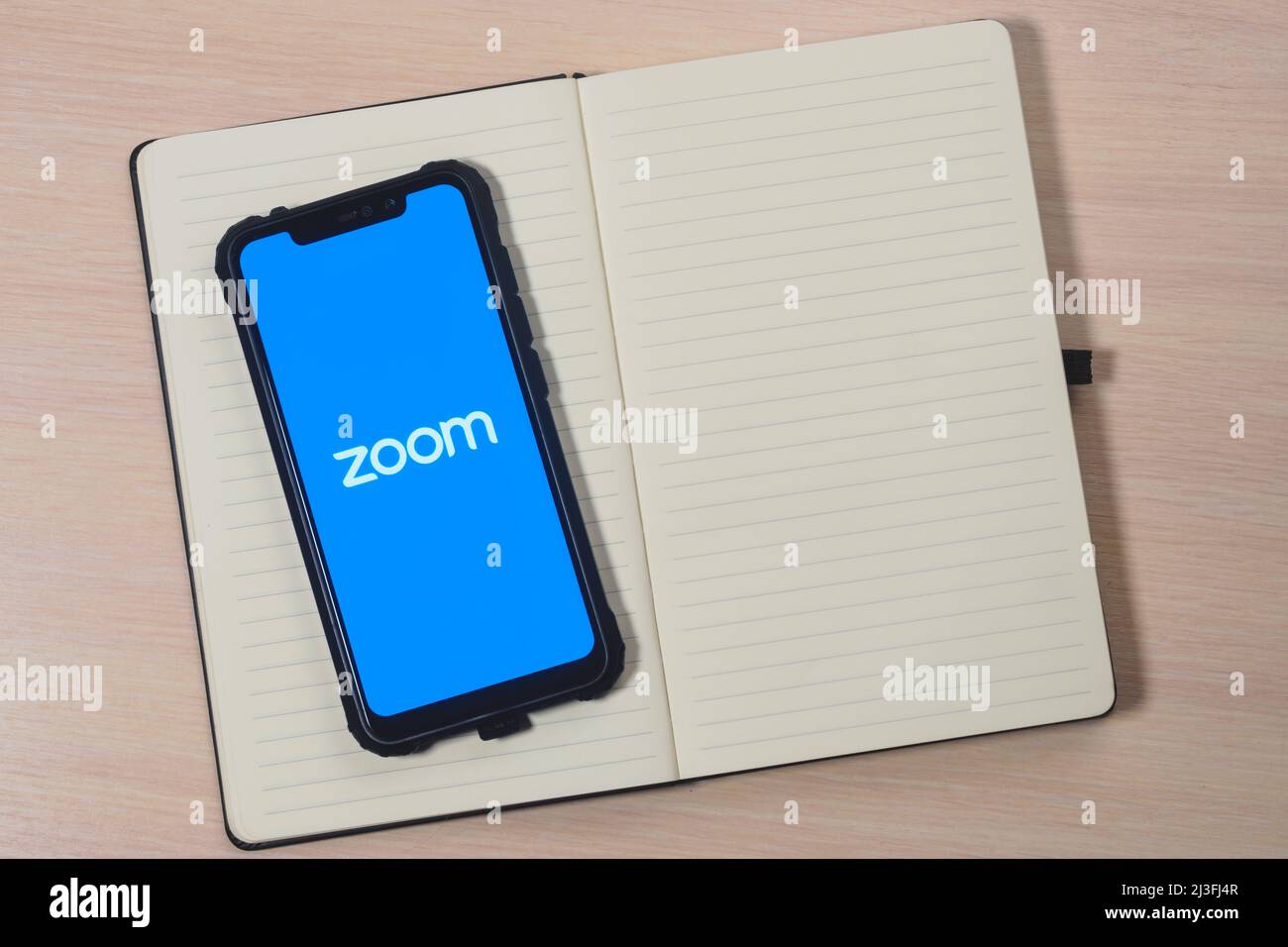 Zoom app logo on the screen smartphone. Zoom Video Communications is a company that provides remote conferencing services. Preparing for an online mee Stock Photo