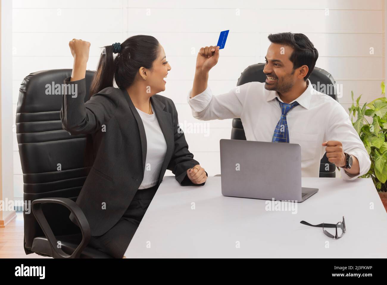 Happy business couple cheering with raising fists after successful transaction using credit card Stock Photo