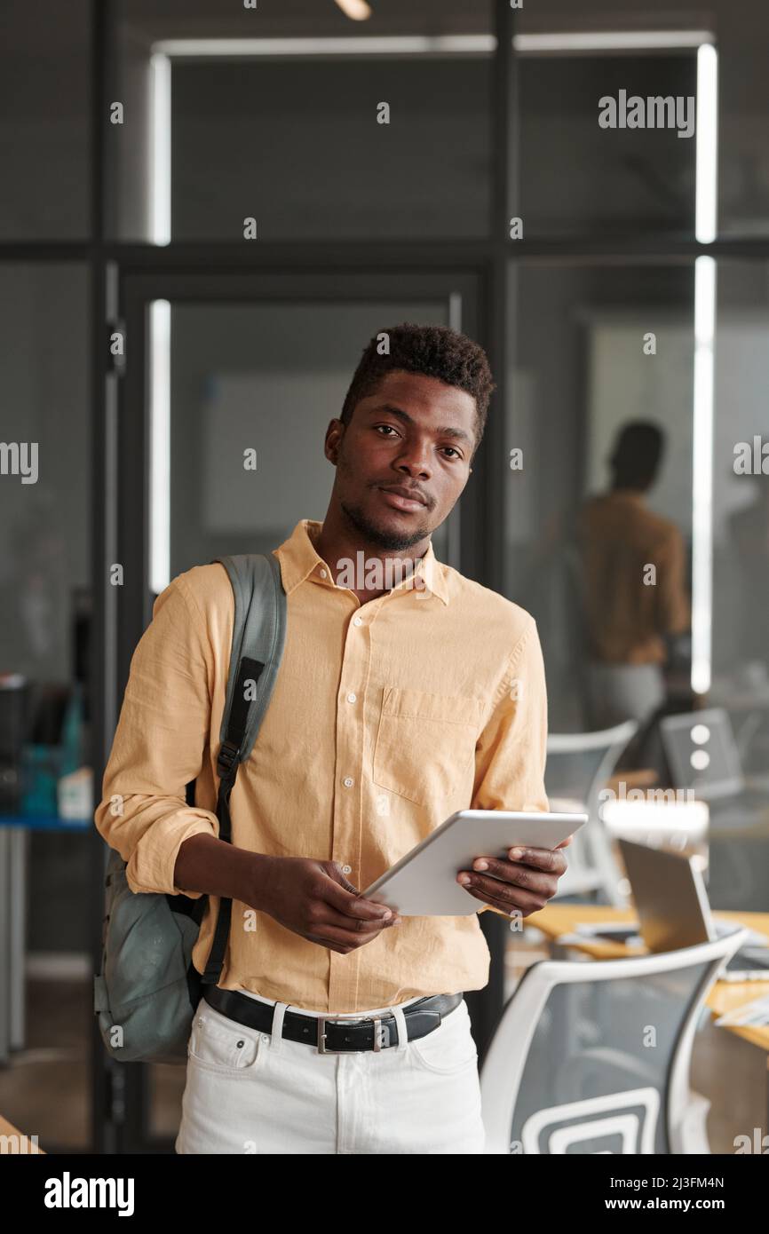 Portrait of serious young black student with satchel using tablet in modern coworking space Stock Photo