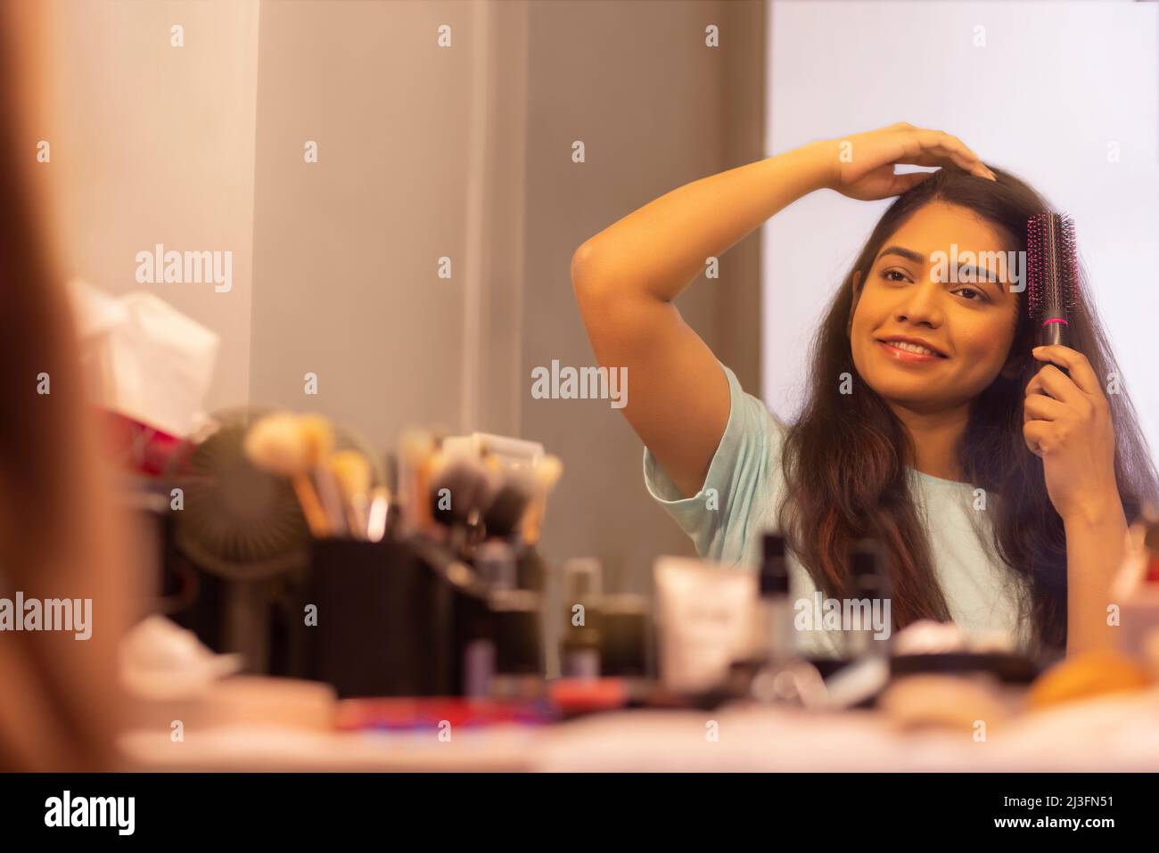 Young woman combing her hair in front of mirror Stock Photo