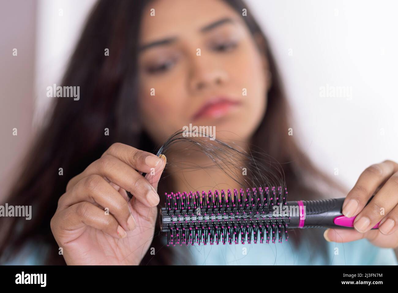 Close-up of Upset woman holding a comb with lost hair Stock Photo