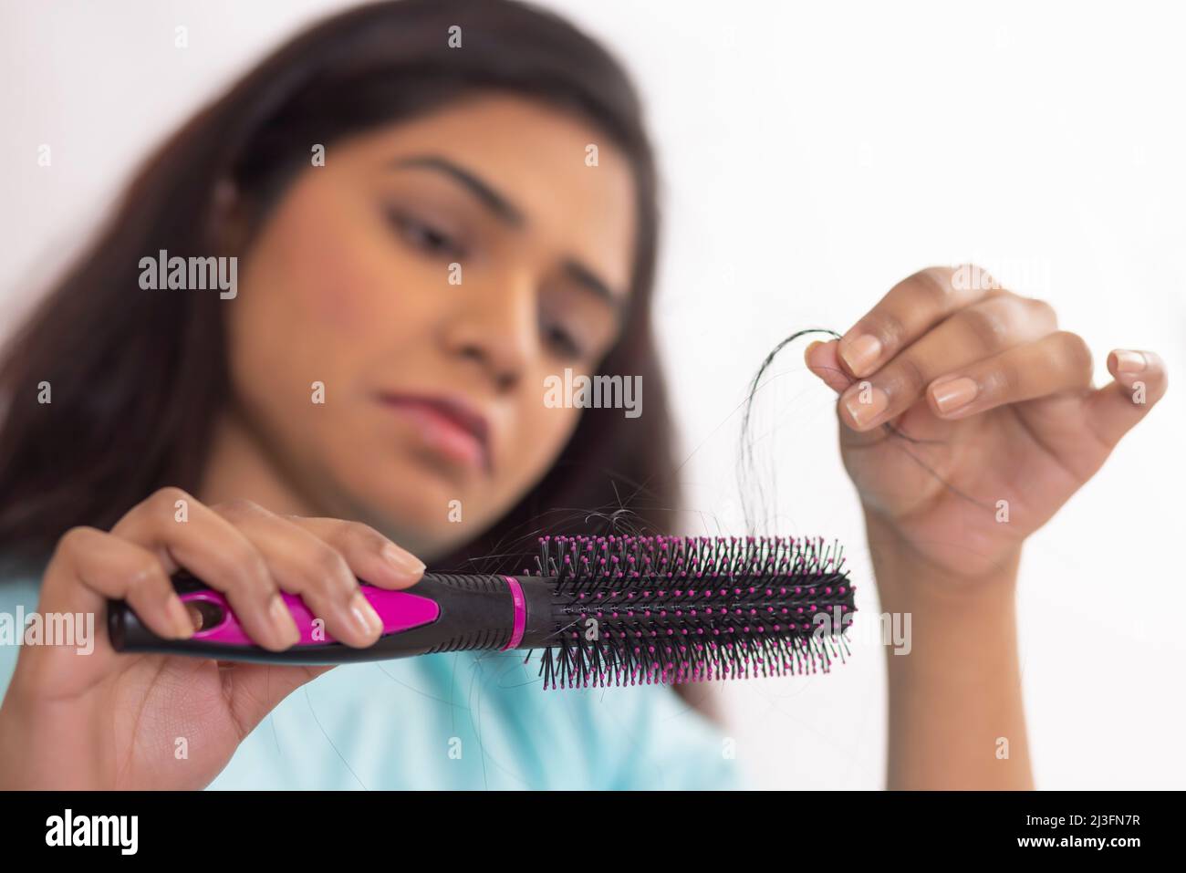 Close-up of Upset woman holding a comb with lost hair Stock Photo