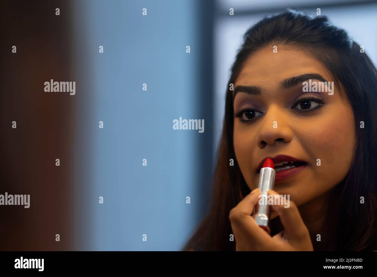 Close-up portrait of young woman applying red lipstick Stock Photo