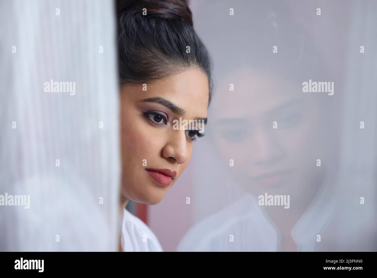 Close-up portrait of a woman looking outside with reflection in window Stock Photo