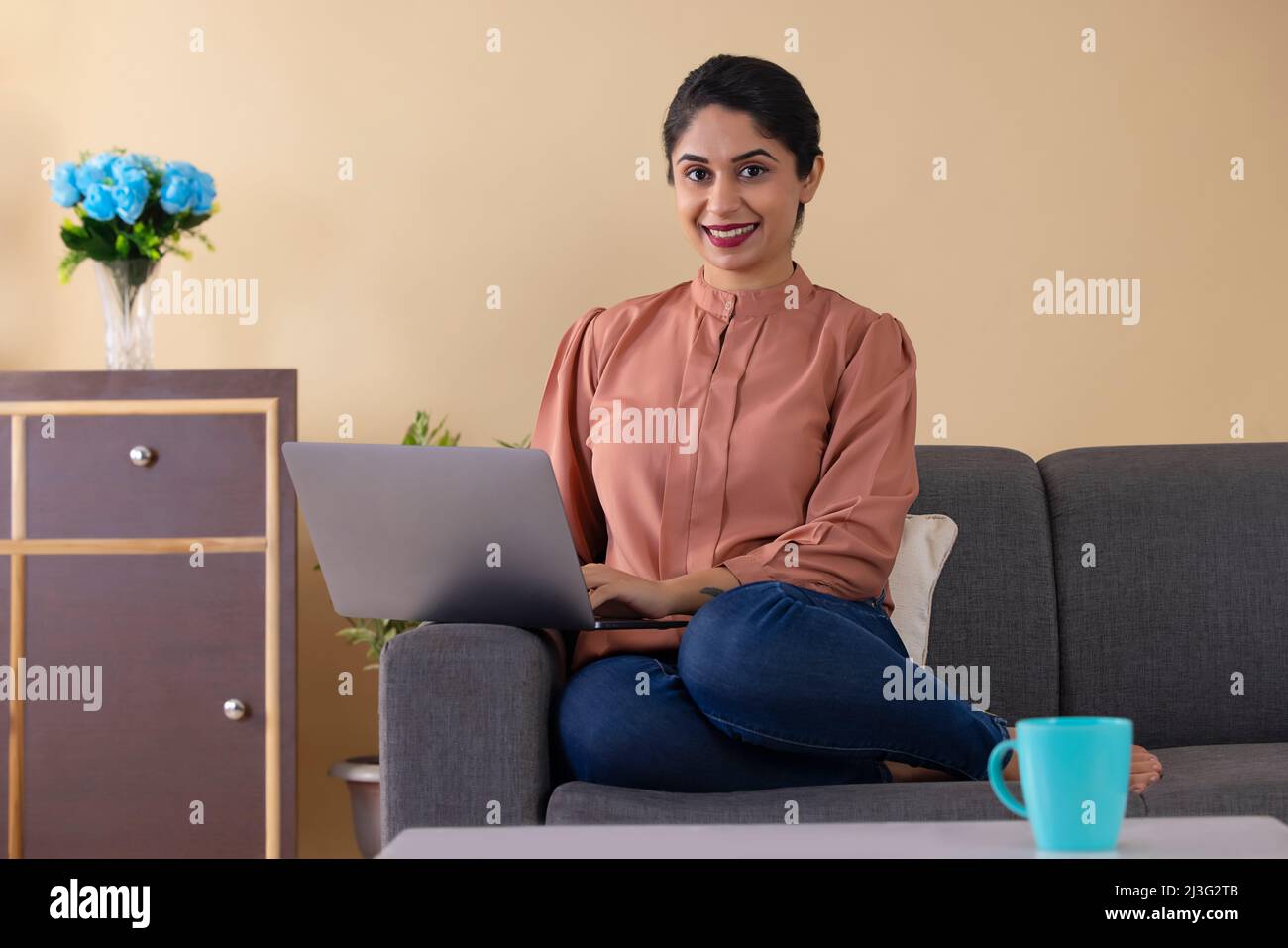 Happy Indian woman working from home using laptop Stock Photo