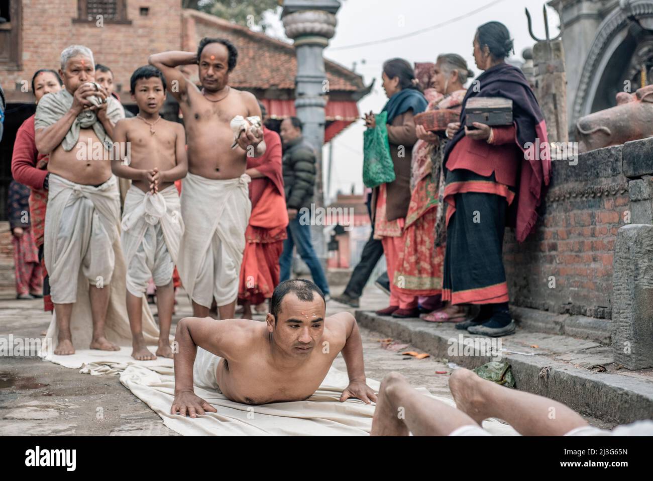 Nepali Hindu devotees offer prayers by rolling on the ground during the Swasthani Brata Katha festival in Bhaktapur, Nepal Stock Photo