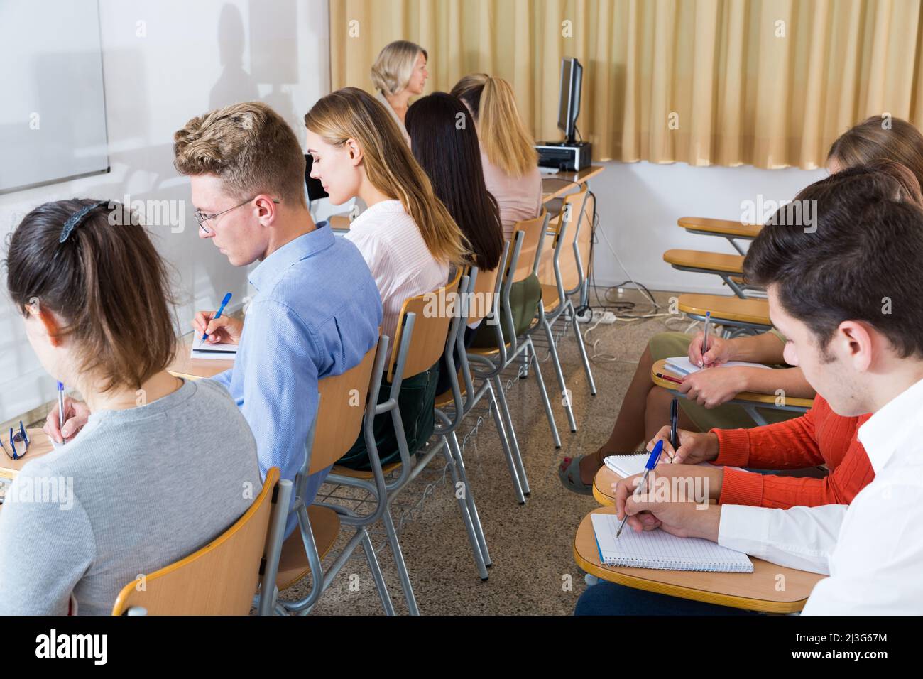 Students writing examination with female professor Stock Photo Alamy